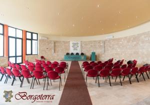 a large room with red chairs and a table at Borgoterra in Martano