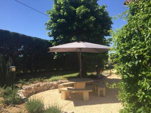 uma mesa de piquenique com um guarda-sol num jardim em Là Grange em Parisot