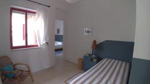 a bedroom with a bed and a chair and a window at The Greek’ House in Bova Marina