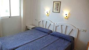 a bedroom with a blue bed and two lights on the wall at Apartamentos Nere in Benidorm