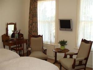 a bedroom with a bed and chairs and a desk and a television at Badger Towers in Cheltenham