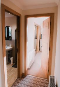 een badkamer met een deur naar een bad en een wastafel bij Greenbank Bed & Breakfast in Montrose