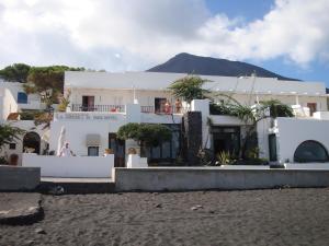 a white building with a mountain in the background at La Sirenetta Park Hotel in Stromboli