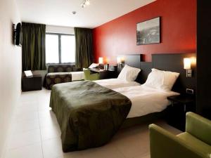 a hotel room with a large bed and a couch at Hotel TTS in Temse