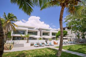 an exterior view of a resort with lounge chairs and palm trees at Les Estivales Beachfront Suites & Penthouses by LOV in Trou aux Biches