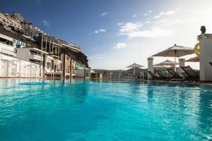 una piscina de agua azul frente a un edificio en IG Nachosol Premium Apartments by Servatur (Adults Only), en Puerto Rico de Gran Canaria