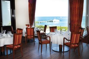a restaurant with tables and chairs with a view of the ocean at Morada Strandhotel Ostseebad Kühlungsborn in Kühlungsborn