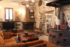 sala de estar con sofá, TV y chimenea en Stone Villa in the Forest, en Mouresi