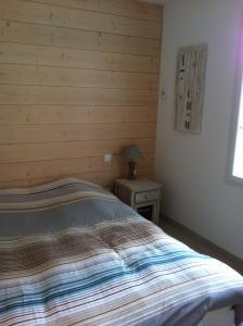 a bed in a bedroom with a wooden wall at La petite rétaise in La Flotte
