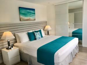 a bedroom with a large white bed with blue accents at Dover Woods Apartments in Christ Church