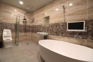 a bathroom with a tub and a toilet and a tv at Hotel Airport in Busan +28 photos