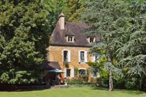 una casa de ladrillo rodeada de árboles y césped verde en Bed & Breakfast Le Moulin Neuf, en Saint-Alvère