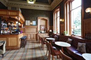 a restaurant with tables and chairs and a bar at Kingsknowes Hotel in Galashiels