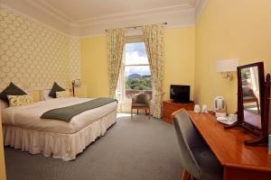 Schlafzimmer mit einem Bett, einem Schreibtisch und einem Fenster in der Unterkunft Kingsknowes Hotel in Galashiels