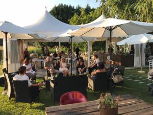 un grupo de personas sentadas en sillas bajo sombrillas blancas en R&B Locanda Le Bighe, en Cona