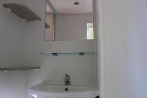 Un baño blanco con lavabo y espejo. en Camping La Fundicion, en Cazalla de la Sierra