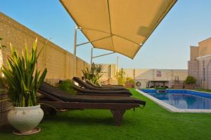 a row of chaise lounges next to a pool at Al Maha Int Hotel Oman in Ghukra