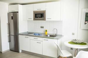 a kitchen with white cabinets and a stainless steel refrigerator at IG Nachosol Atlantic & Yaizasol by Servatur - Adults Only in Puerto Rico de Gran Canaria