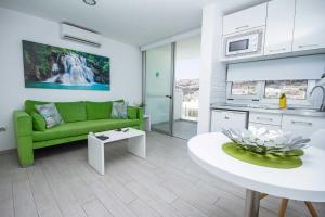 a living room with a green couch and a table at IG Nachosol Atlantic & Yaizasol by Servatur - Adults Only in Puerto Rico de Gran Canaria