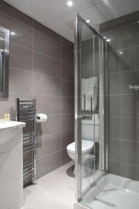 a bathroom with a glass shower and a toilet at Kensington Gardens Hotel in London