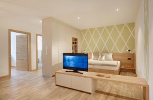 ein Wohnzimmer mit einem TV und einem Bett in der Unterkunft Appartments Waage in Brixen