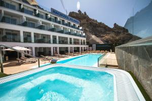 a hotel with a swimming pool with a mountain in the background at IG Nachosol Atlantic & Yaizasol by Servatur - Adults Only in Puerto Rico de Gran Canaria