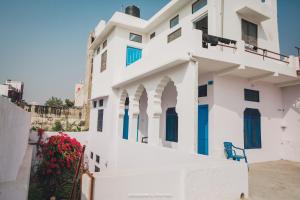 a white house with blue doors and flowers at Rajguru guest house in Pushkar