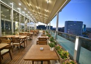 ein Restaurant mit Tischen und Stühlen auf einem Balkon in der Unterkunft Güvenay Business Hotel in Ankara