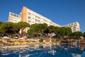 un hotel con piscina frente a un edificio en htop Caleta Palace #htopBliss, en Platja d'Aro