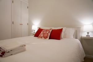 1 dormitorio con cama blanca y almohadas rojas en Casa da Laurindinha, en Ponte de Lima