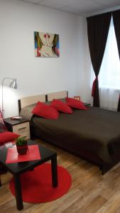 ペルミにあるManhattan Apartmentsのベッドルーム1室(赤い枕とテーブル付きのベッド1台付)