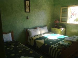 een groene kamer met 2 bedden en een raam bij Complexe Collier D' Ambre in Imilchil