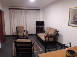 a living room with chairs and a couch and a tv at Dpto San Martin in Salta