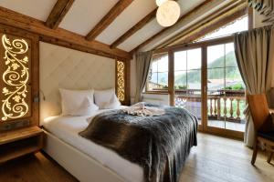 a bedroom with a bed and a large window at Oberlechtaler Hof Boutique Hotel in Holzgau