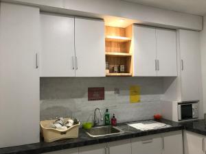 a kitchen with white cabinets and a sink at The Colour Hostel in Pontianak