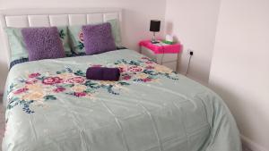 a bed with a white comforter with flowers on it at AdB in Hemel Hempstead