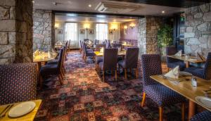 a dining room with tables and chairs and a stone wall at Strangford Arms Hotel in Newtownards
