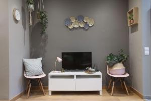 a living room with a tv and two pink chairs at Suite Place Barcelona Còrsega in Barcelona