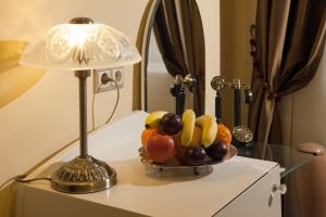 a table topped with a bowl of fruit next to a lamp at Barokk Hotel Promenád in Győr