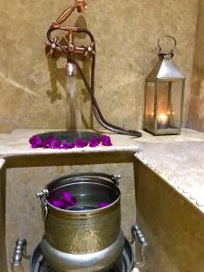 einen Eimer Wasser mit lila Blumen und einer Laterne in der Unterkunft Palais Akki in Marrakesch