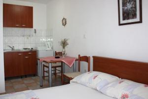 a bedroom with a bed and a table and a kitchen at Budget Apartments Batkoski Pag in Pag