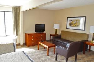 Extended Stay America Suites - Omaha - West في أوماها: غرفة معيشة مع أريكة وتلفزيون