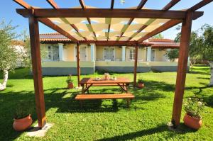 Almiros Beach的住宿－自由公寓，院子里木凉棚下的野餐桌