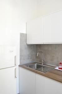 eine weiße Küche mit einer Spüle und einem Kühlschrank in der Unterkunft Casa vacanze Little Queen in Rom