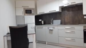 una cocina con armarios blancos y una silla. en Olomouc NEW1, en Olomouc 20 fotos más