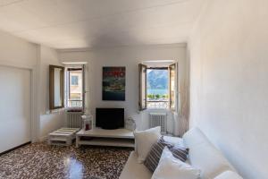 a living room with a white couch and a tv at Family Nest Overlooking Lake Como - by Rent All Como in Argegno