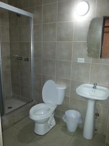 a bathroom with a toilet and a sink and a shower at Hotel Pension Corona in Panama City