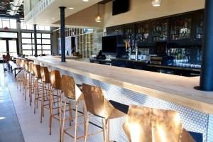 a bar with a row of chairs and a wooden counter at Cavalry Court, by Valencia Hotel Collection in College Station