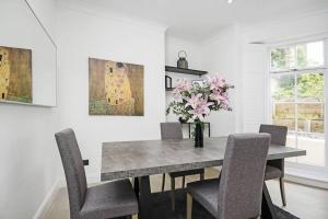 una mesa de comedor con sillas y un jarrón de flores en Bright Luxurious Flat in Little Venice en Londres