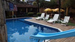 a group of chairs and umbrellas next to a swimming pool at Pousada Villa Virgínia Guarujá in Guarujá